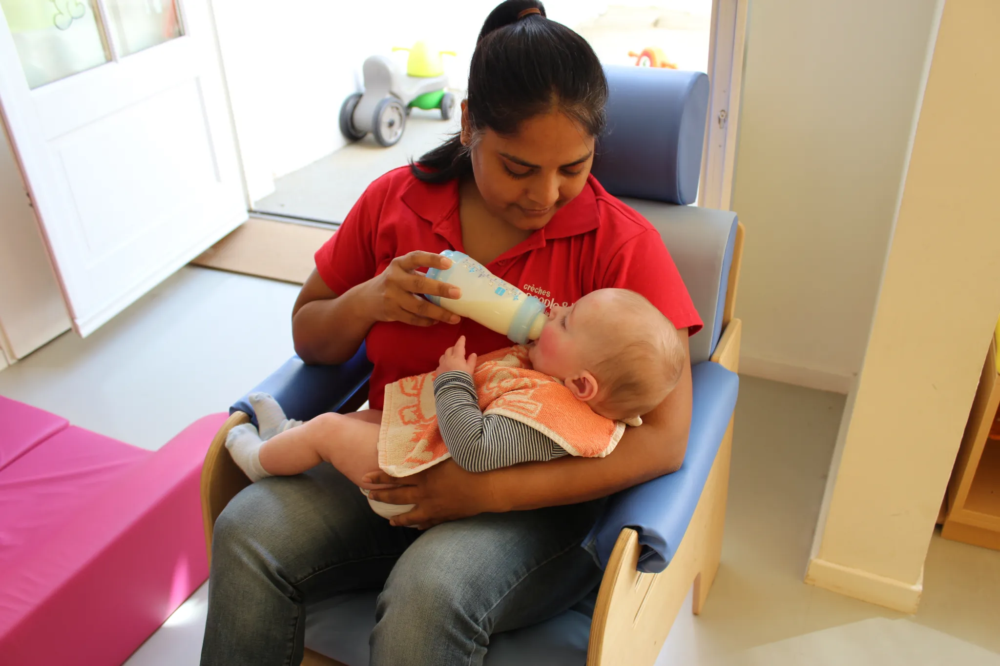 Une éducatrice nourrit un bébé avec un biberon.