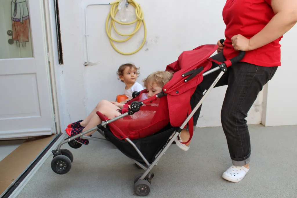 Femme poussant une poussette avec deux enfants.